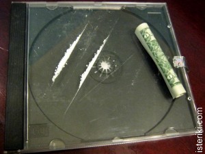 Коробка от компакт-диска с дорожками наркотика и свёрнутая в трубочку долларовая купюра