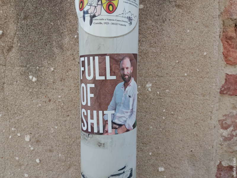 Наклейка на столбе с каким-то мужиком и надписью "Full of shit"