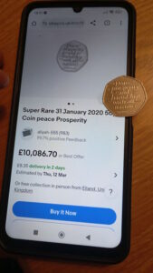 Super rare coin ebay listing on the phone with the same coin lying on top